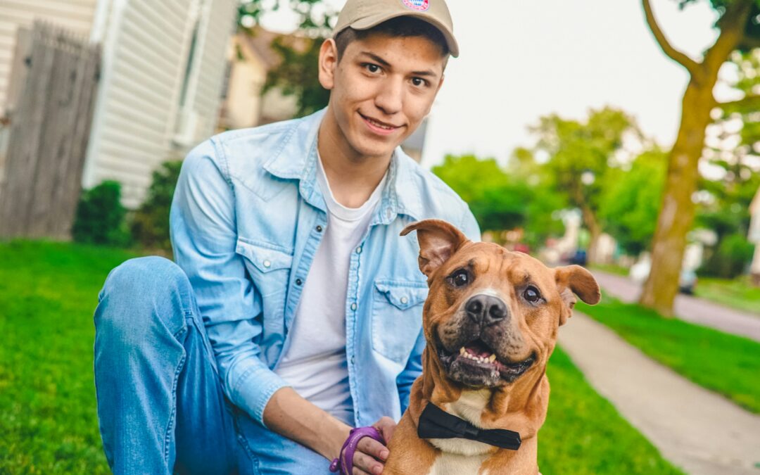 young man kneeling next to his newly adopted happy dog